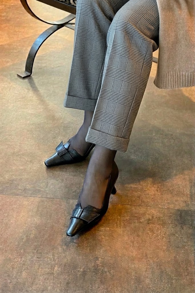 Women's black bow pumps with almond toe and mid spool heel - Worn view